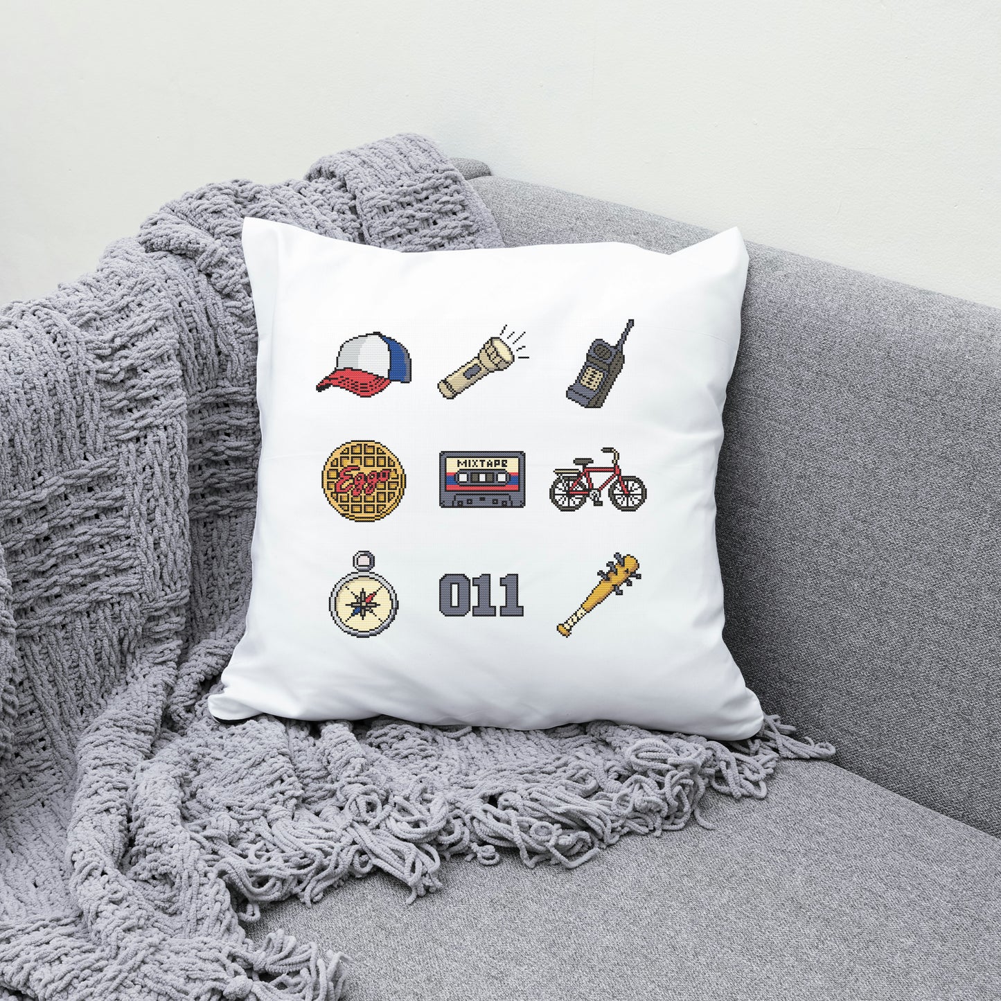Decorative pillow with embroidered icons on a gray couch