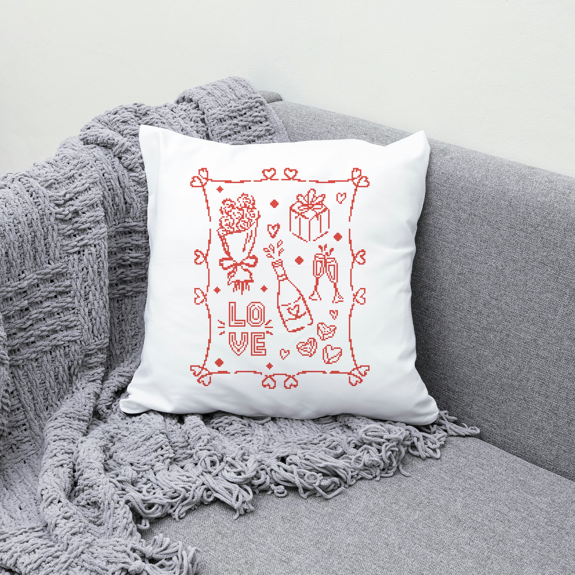 White pillow with red 'LOVE' design on a gray couch