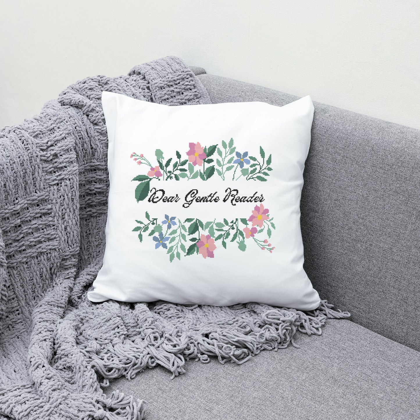 Decorative pillow with floral design and text on a gray couch