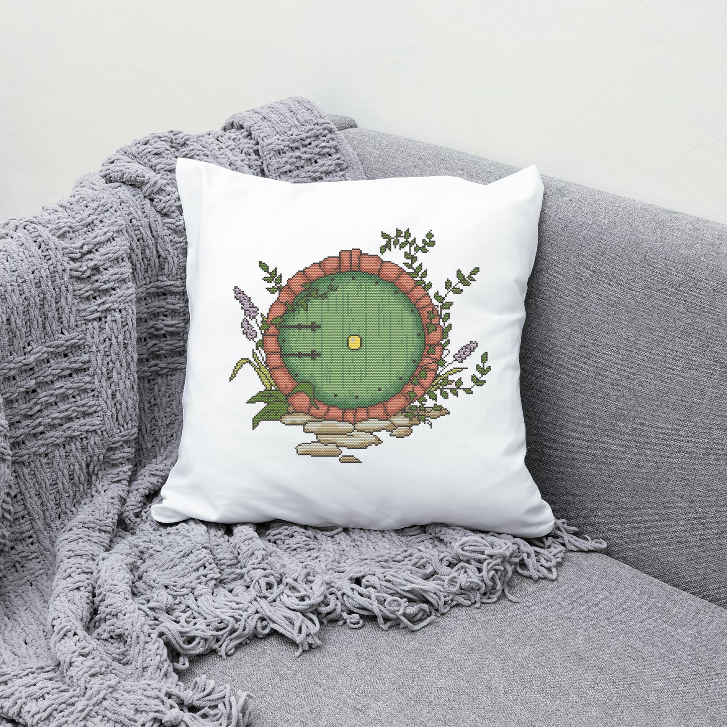 Decorative pillow with a hobbit door design on a gray couch.
