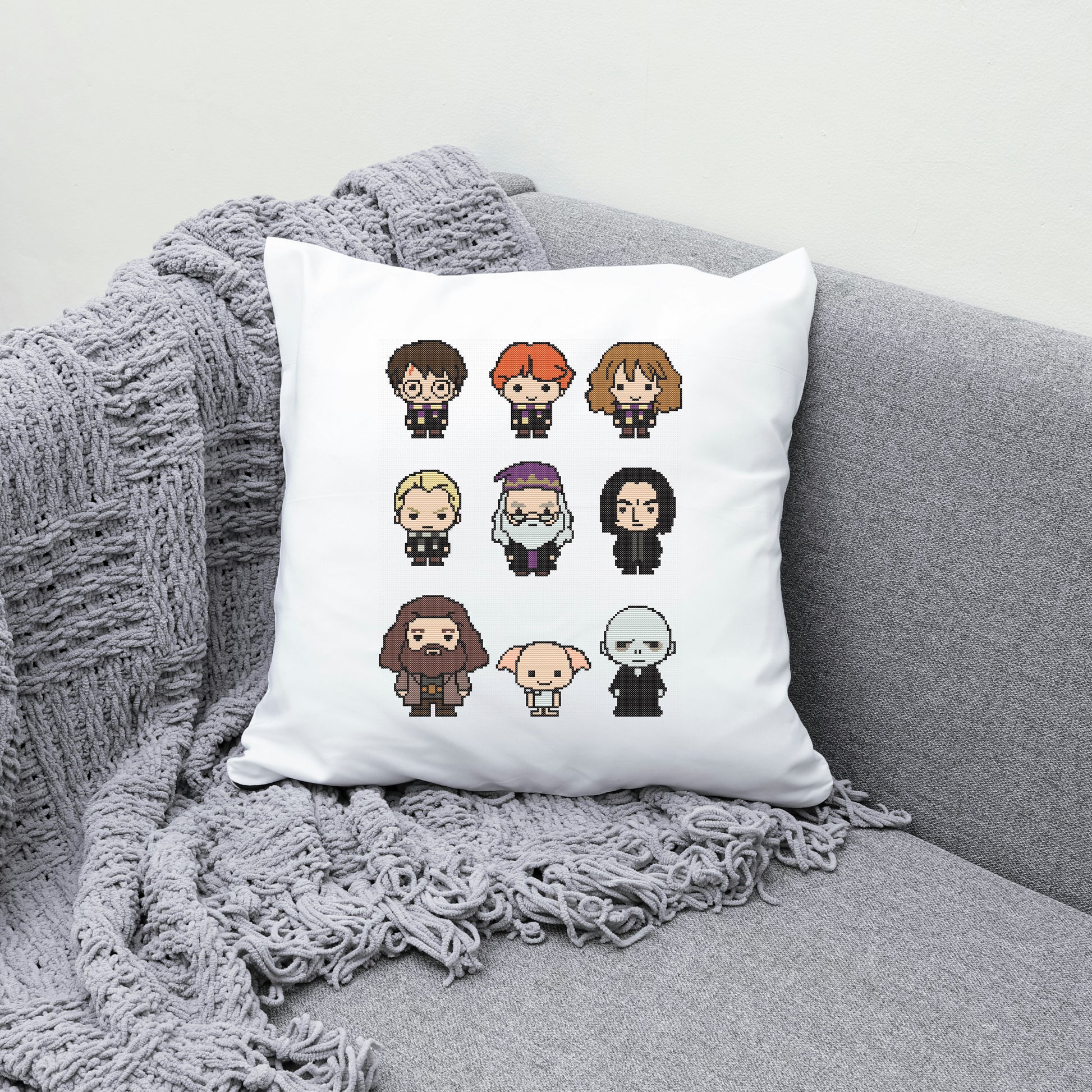 White pillow with pixel art character illustrations on a gray couch