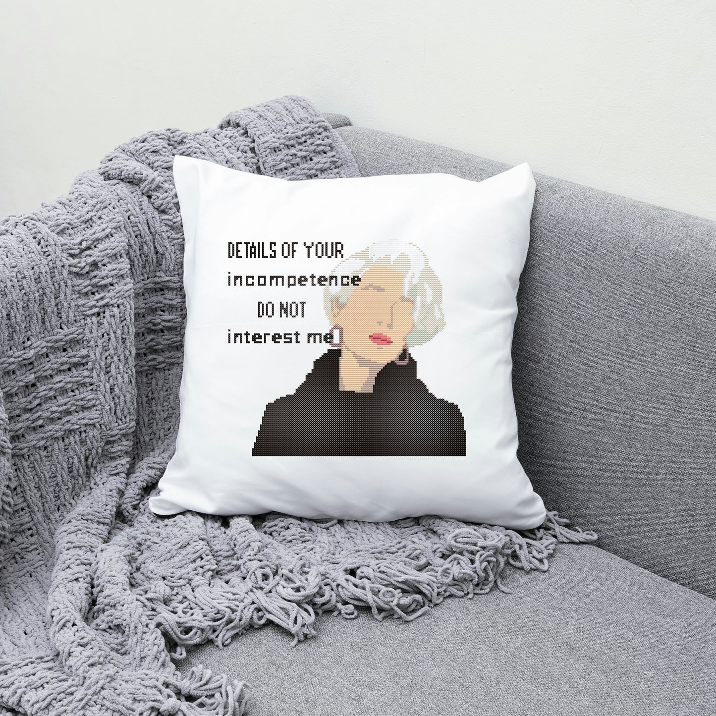 Pillow with a quote and a person's face on a gray couch with a blanket.
