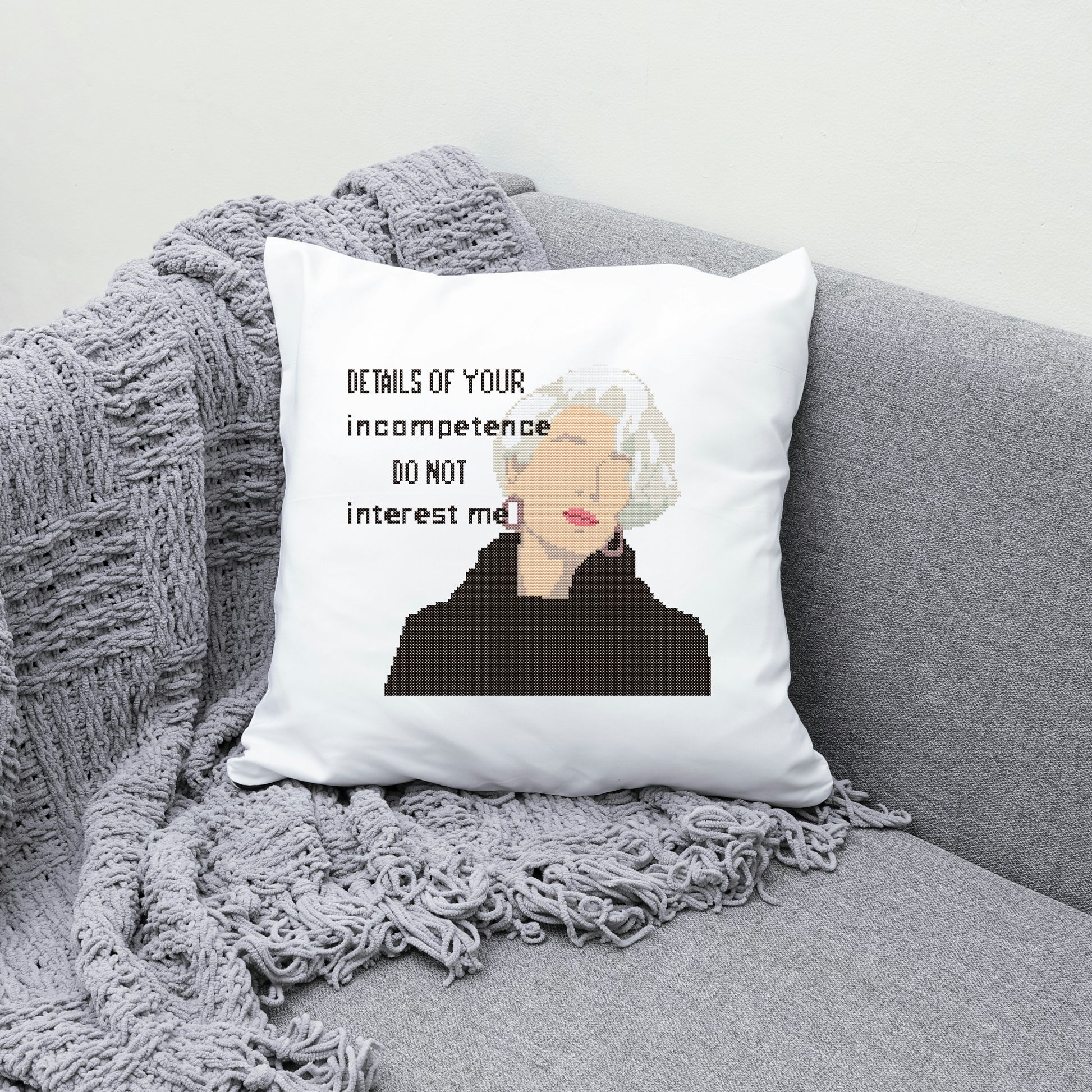 Pillow with a quote and a person's face on a gray couch with a blanket.
