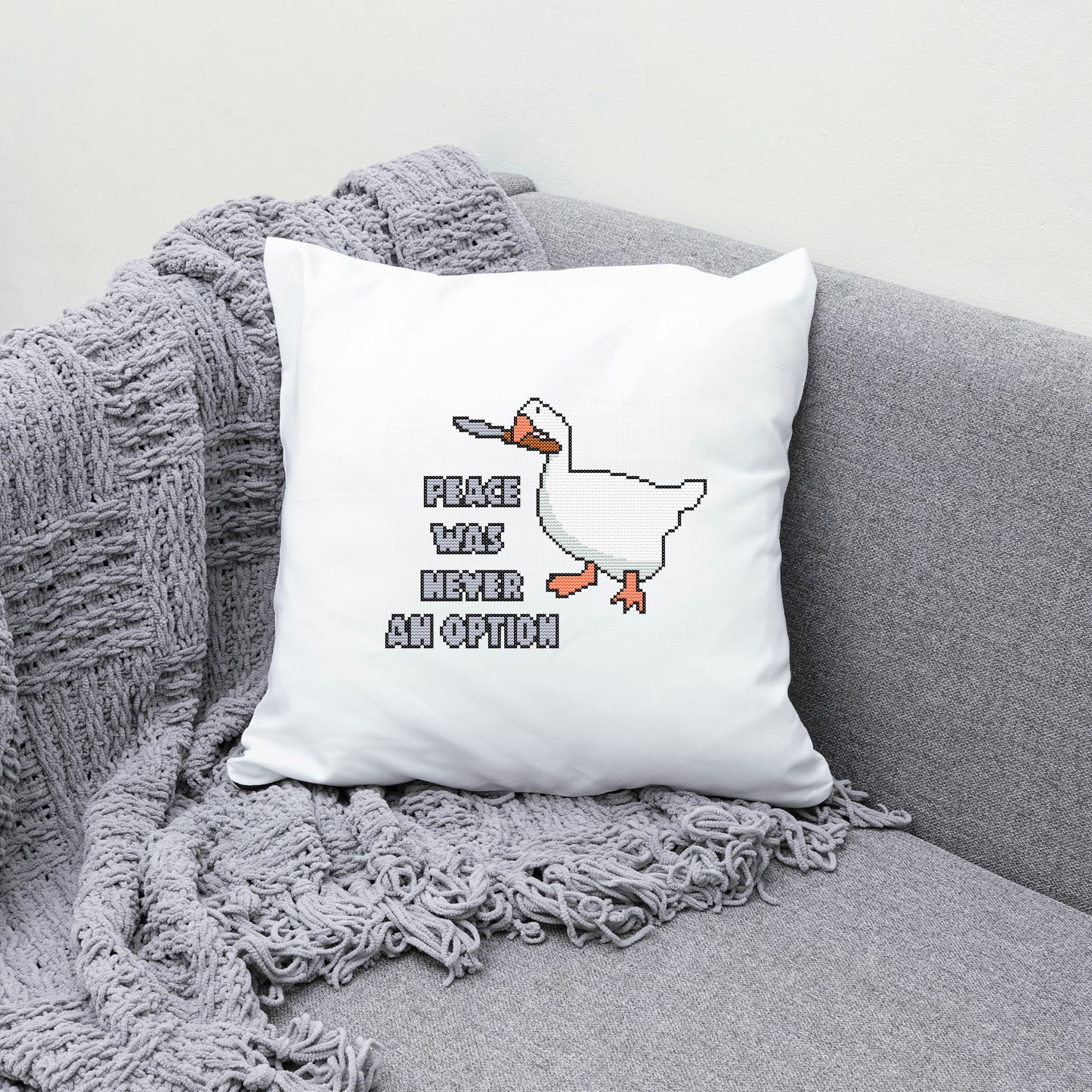 White pillow with a duck graphic and text on a gray couch