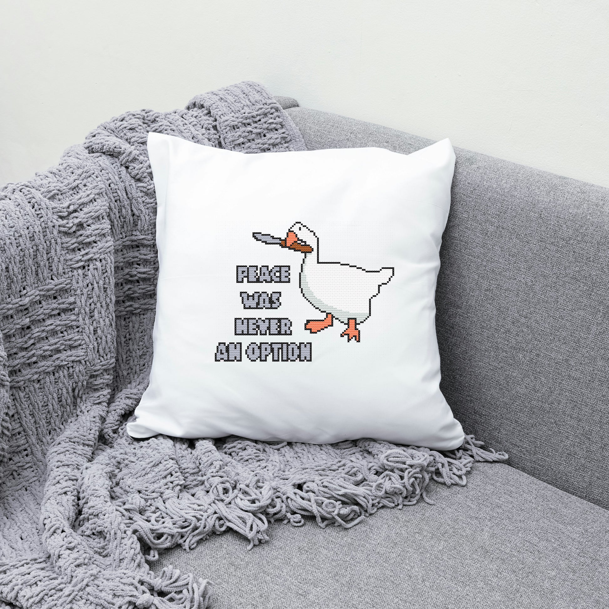 White pillow with a duck graphic and text on a gray couch