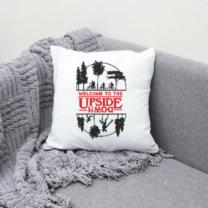 White pillow with 'Welcome to the Upside Down' design on a gray couch.