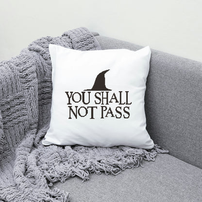 White pillow with 'You Shall Not Pass' text on a gray couch with a textured blanket.