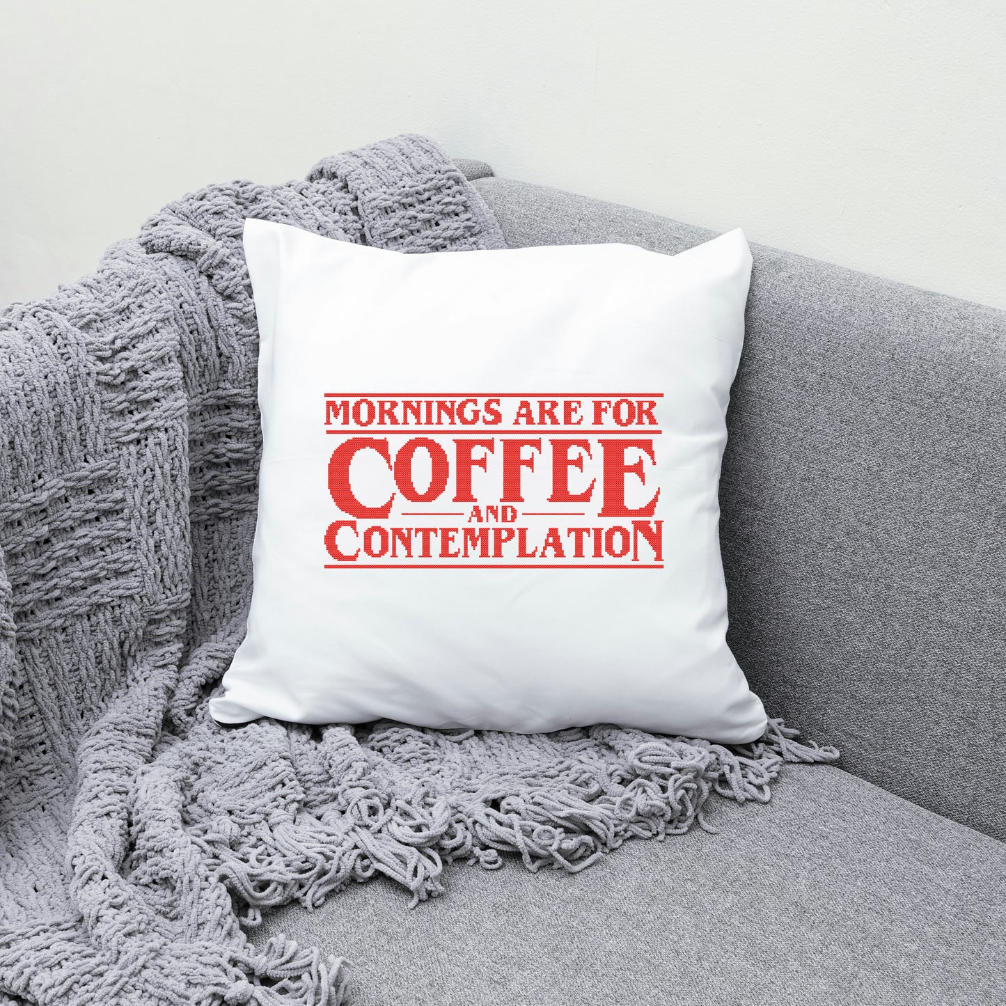 White pillow with red text on a gray couch