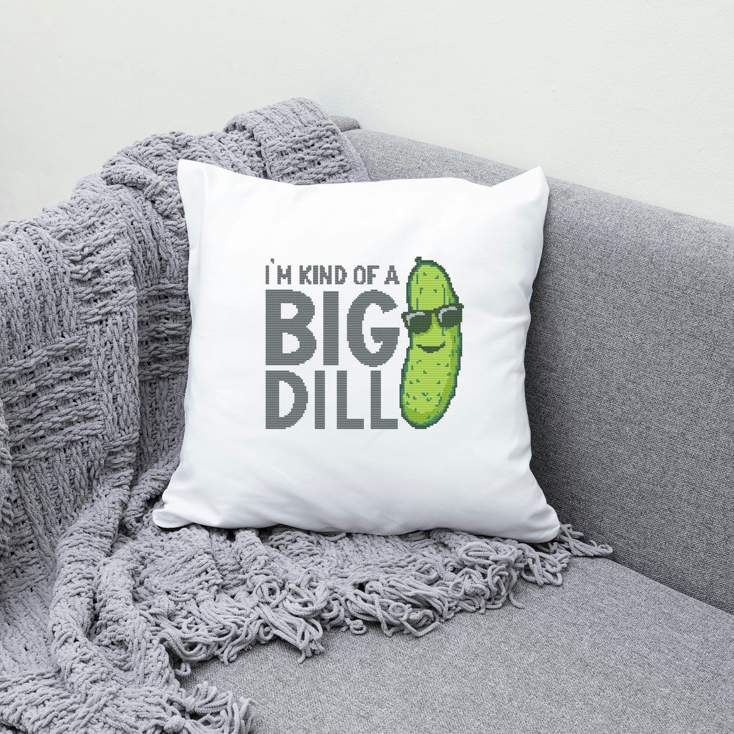 White pillow with a pickle graphic and text on a gray couch