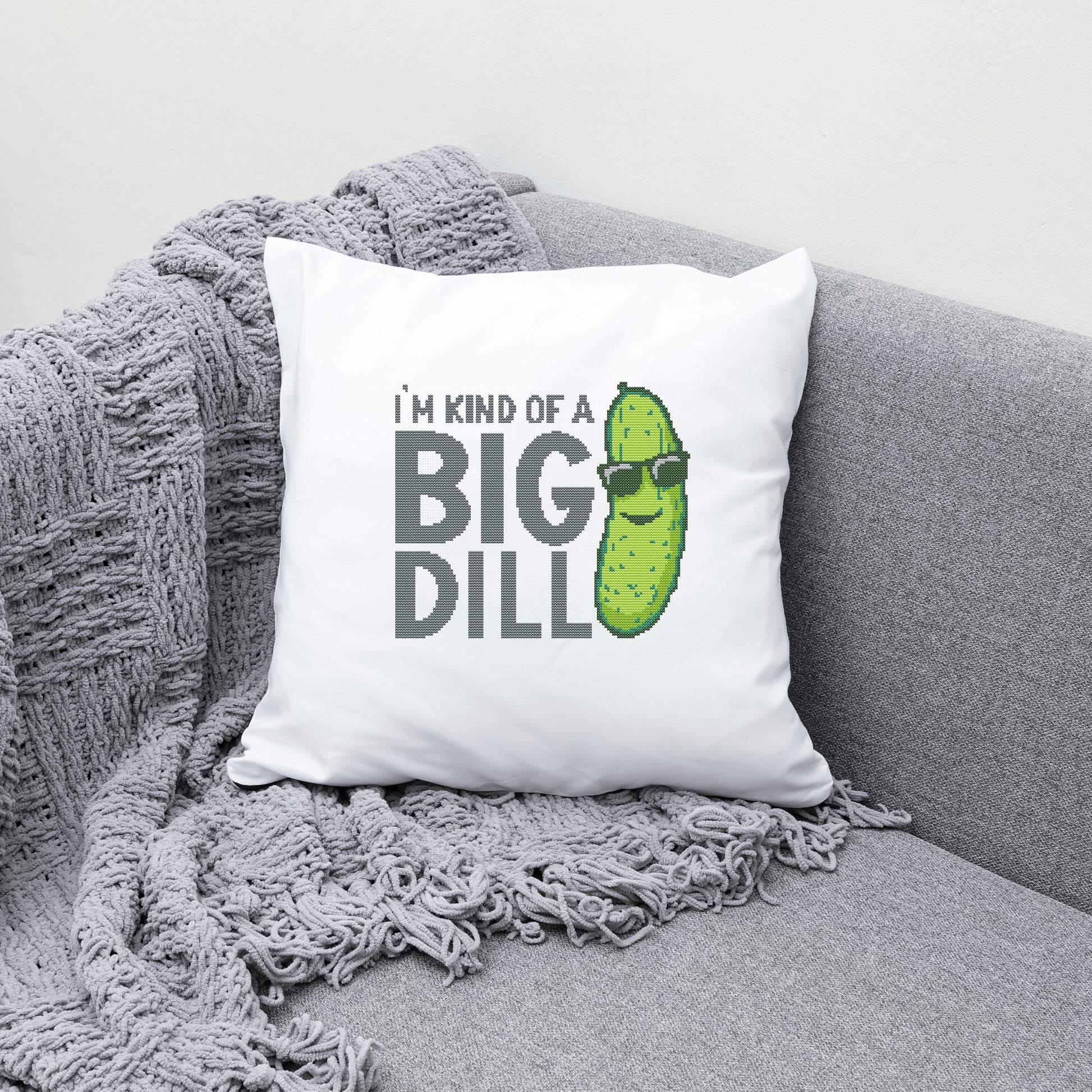 White pillow with a pickle graphic and text on a gray couch