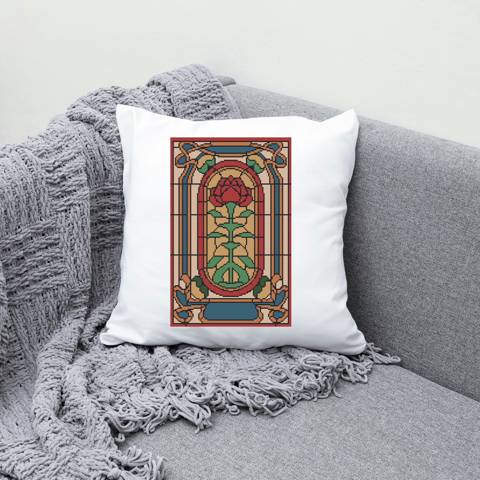 Decorative pillow with stained glass rose design on a gray couch.