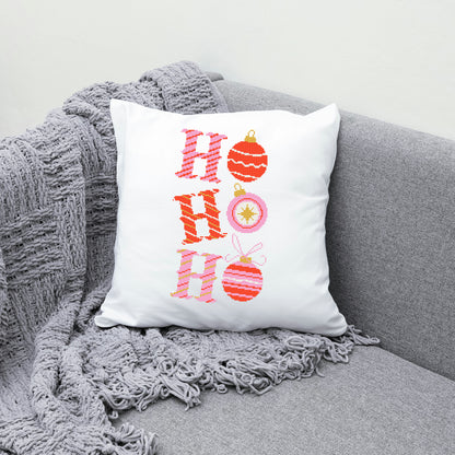 Decorative pillow with 'HO HO HO' and Christmas ornaments on a gray couch.