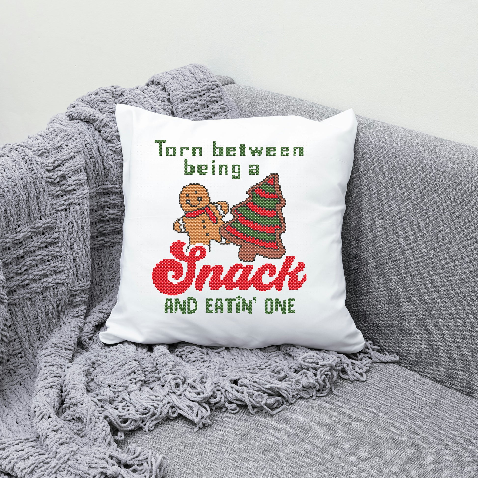 Decorative pillow with Christmas-themed text and graphics on a gray couch.
