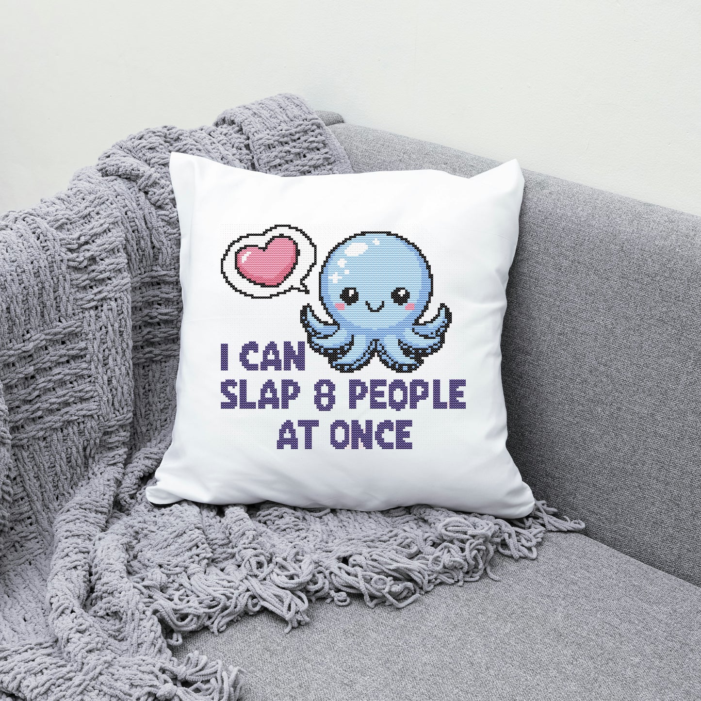 White pillow with a blue octopus design and text on a gray couch.