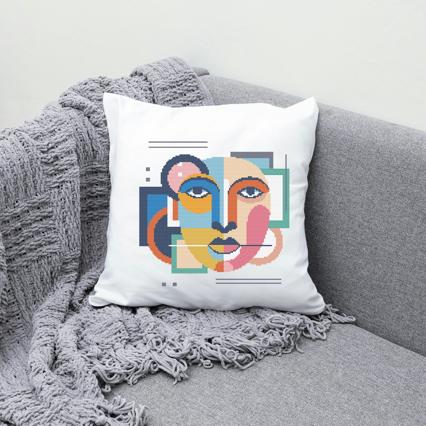 Decorative pillow with colorful face design on a gray couch