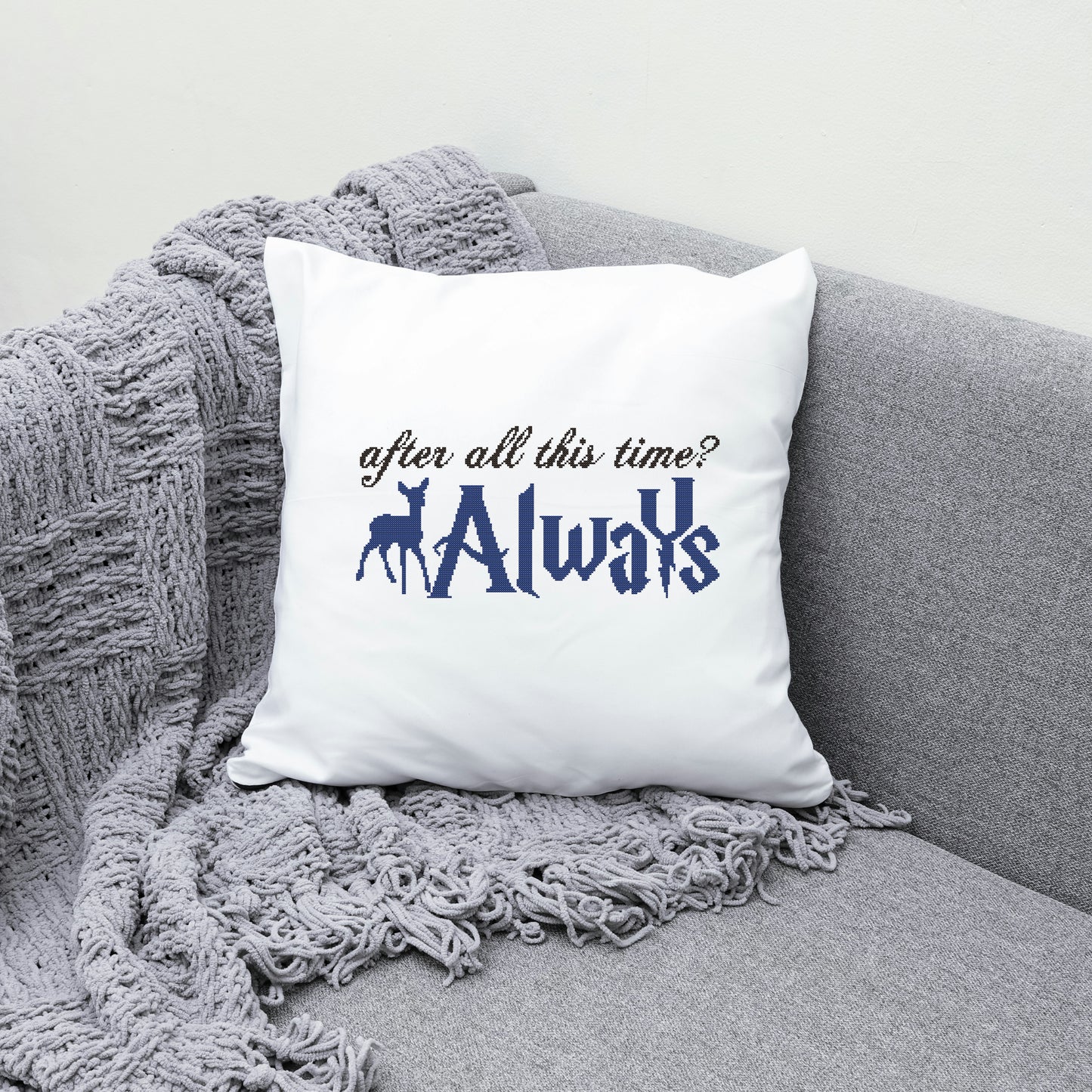 White pillow with 'After all this time? Always' text on a gray couch with a gray blanket.