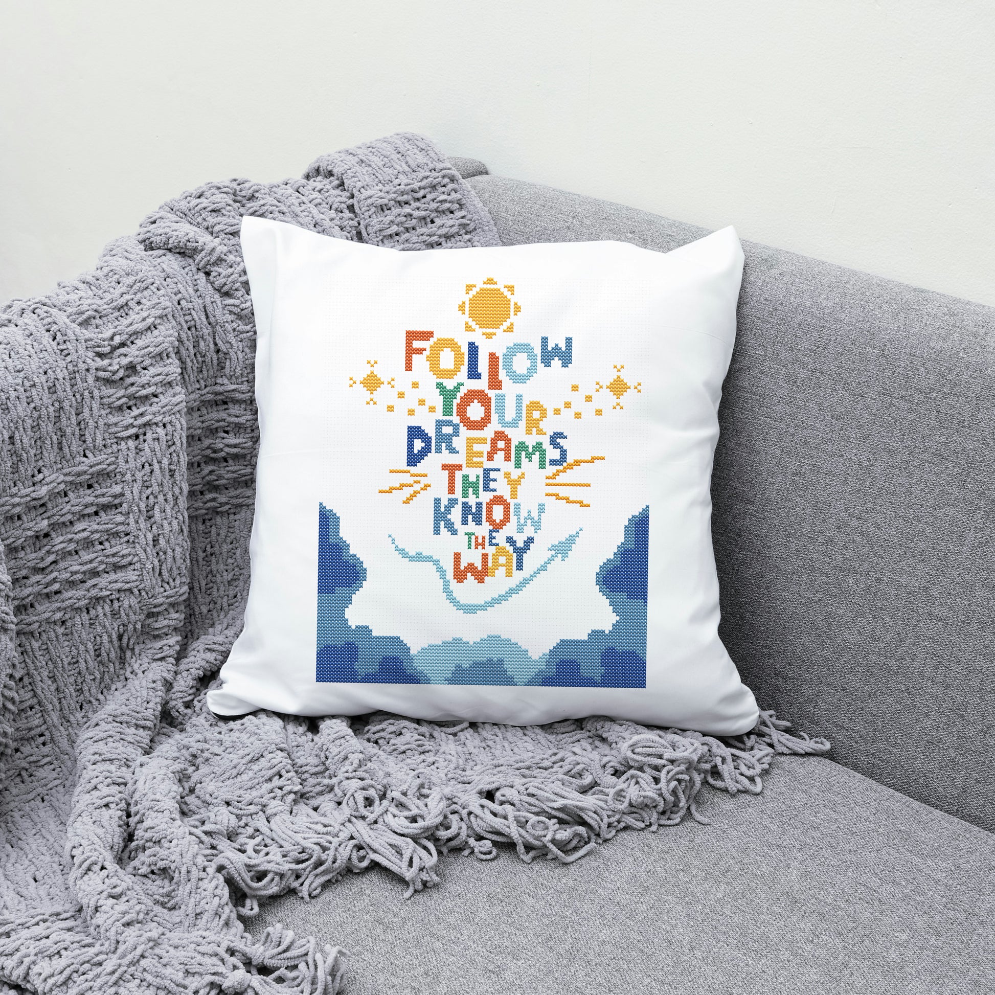Decorative pillow with 'Follow your dreams, they know the way' text on a gray couch.