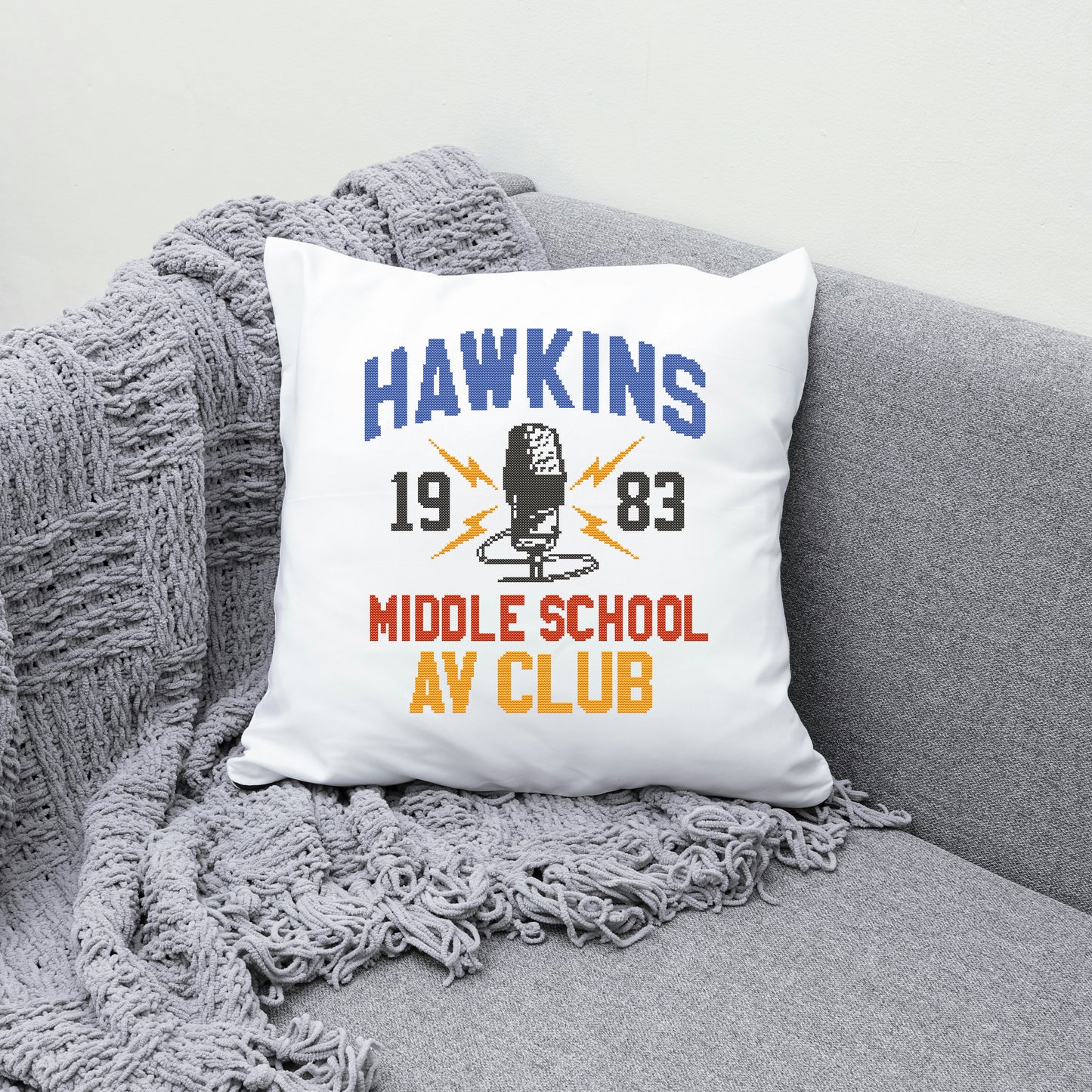 Pillow with 'Hawkins Middle School AV Club' design on a gray couch