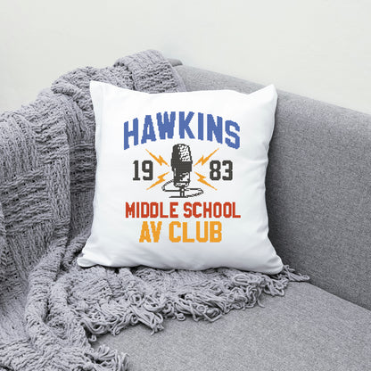 Pillow with 'Hawkins Middle School AV Club' design on a gray couch