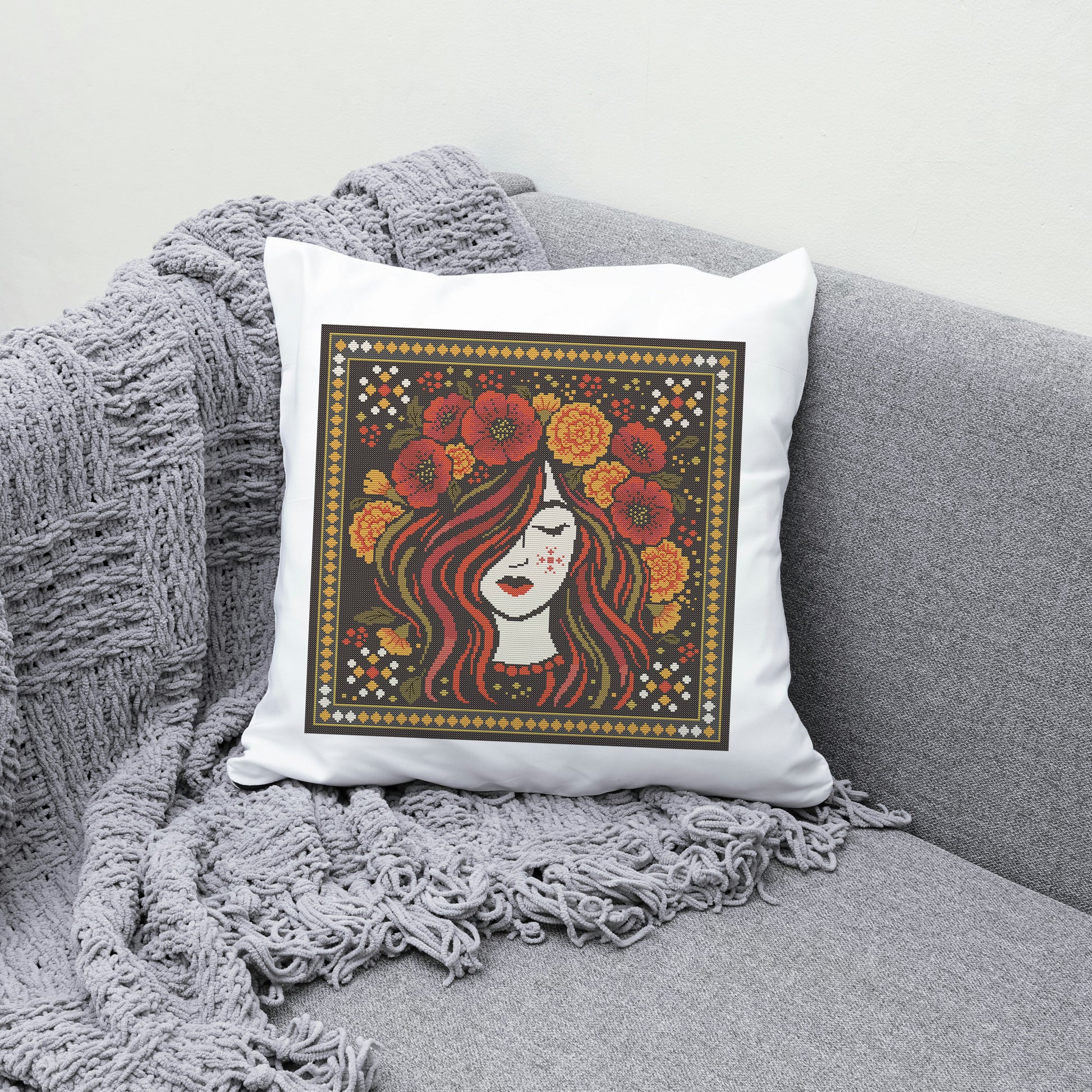 Decorative pillow with a woman's face and floral design on a gray couch.