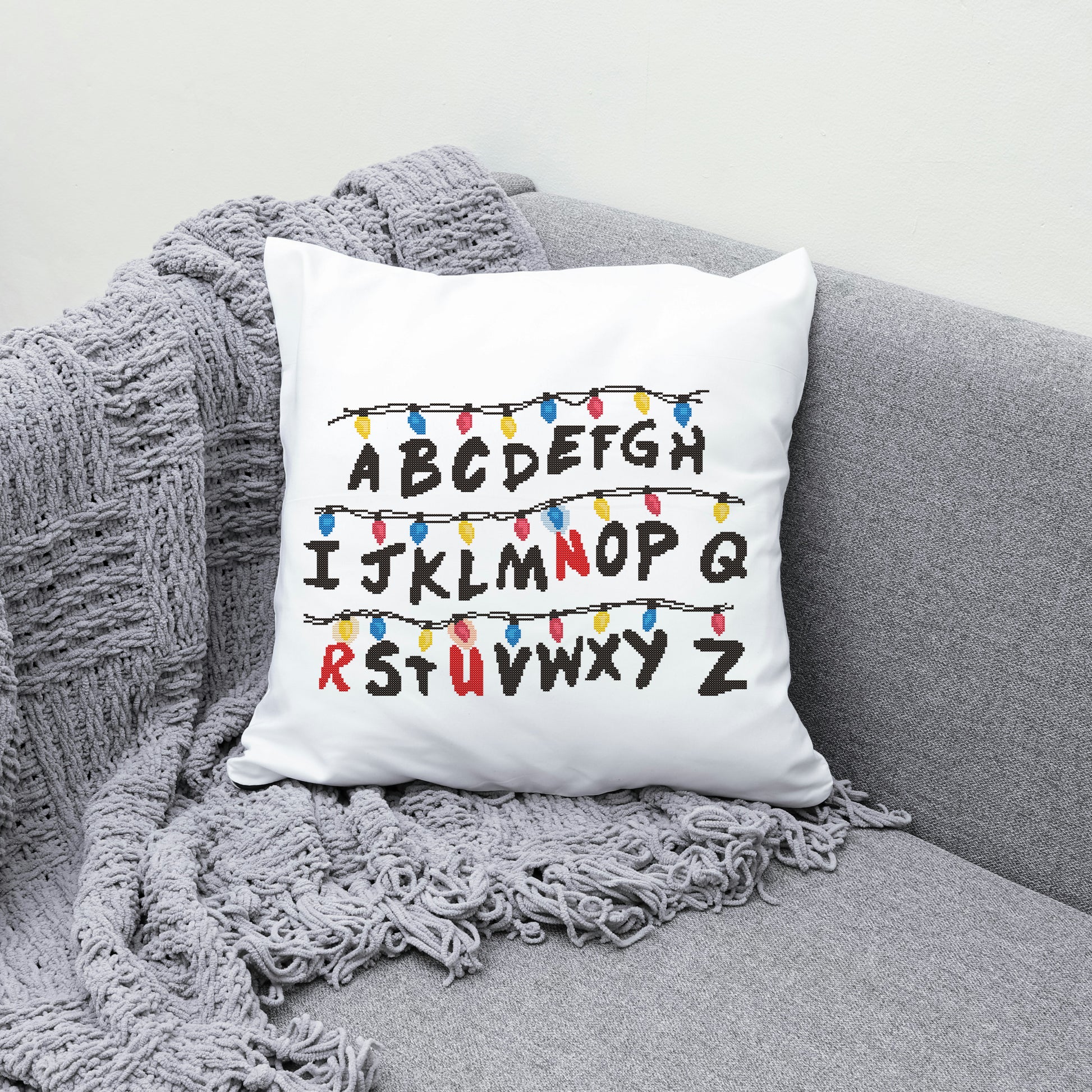 White pillow with alphabet design on a gray couch