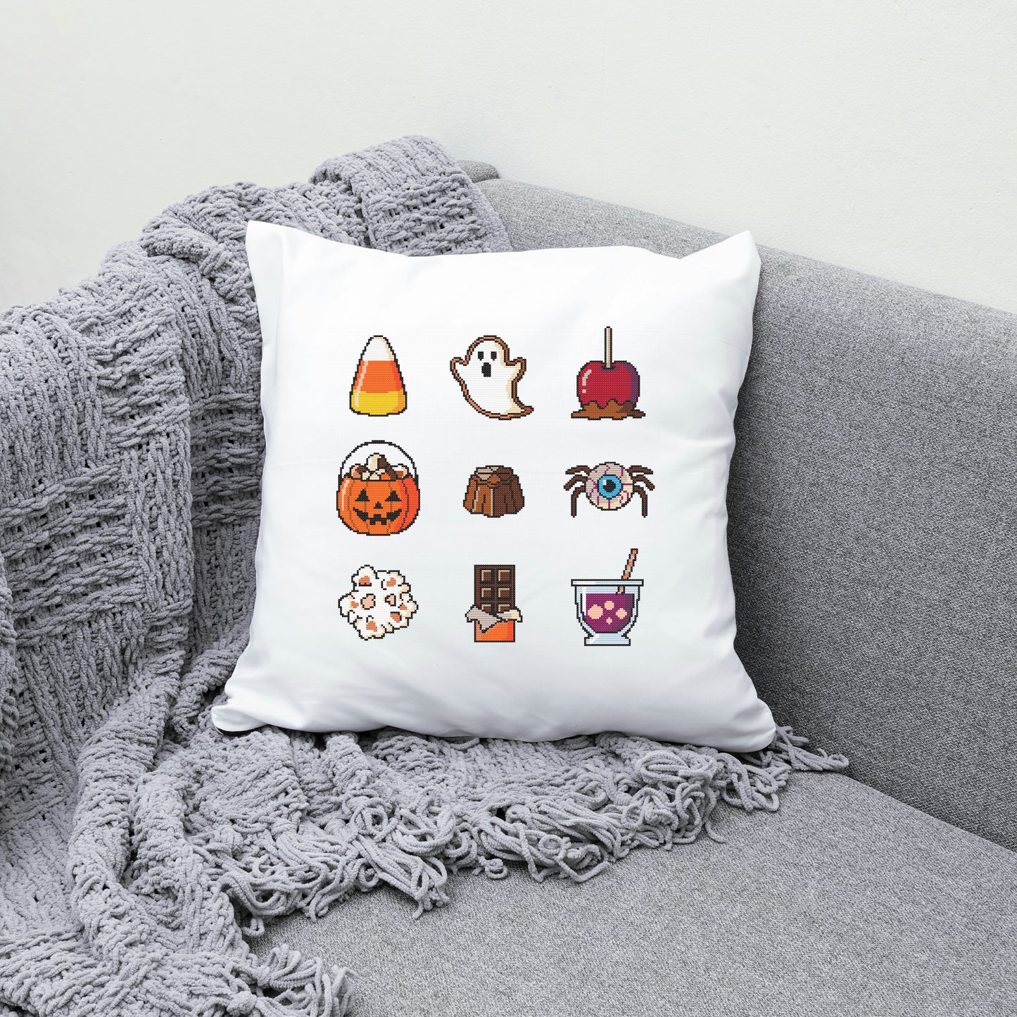 White pillow with Halloween-themed icons on a gray couch