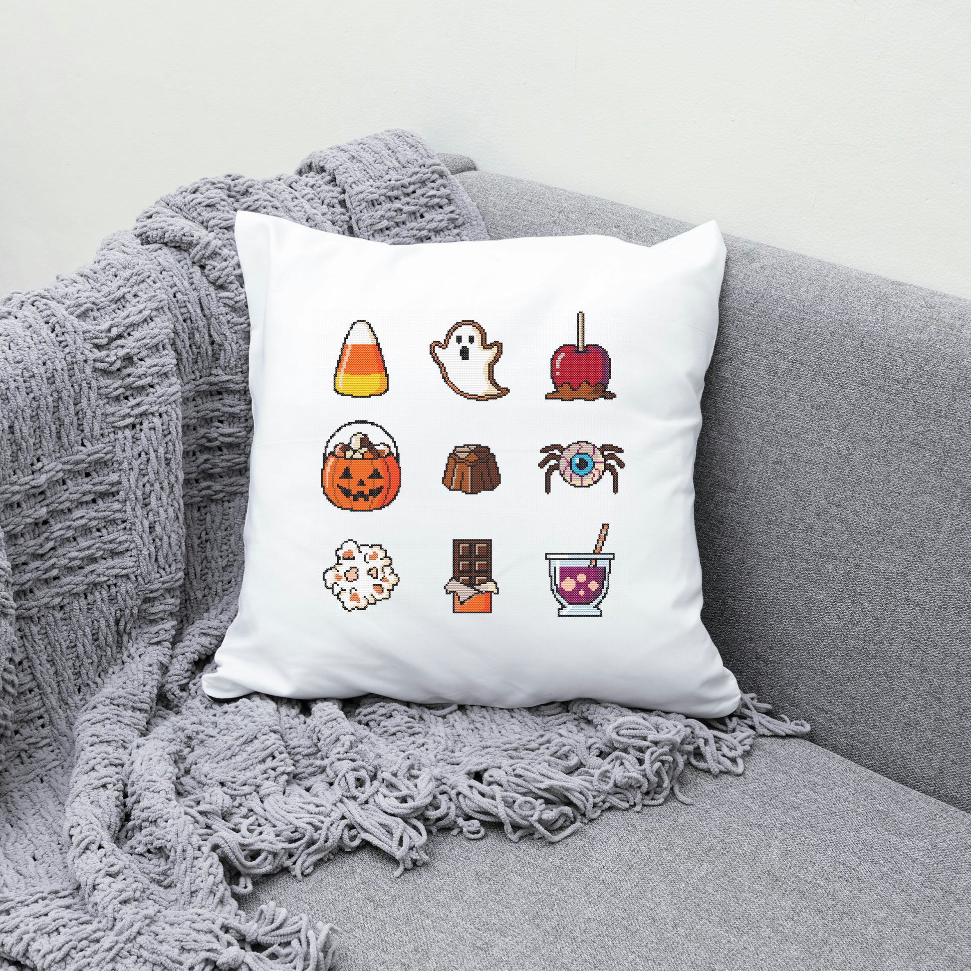 White pillow with Halloween-themed icons on a gray couch