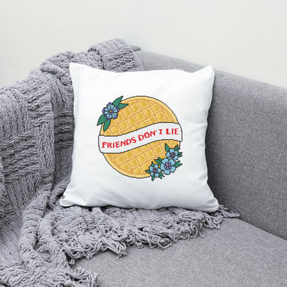 Pillow with pineapple design and 'Friends Don't Lie' text on a gray couch.
