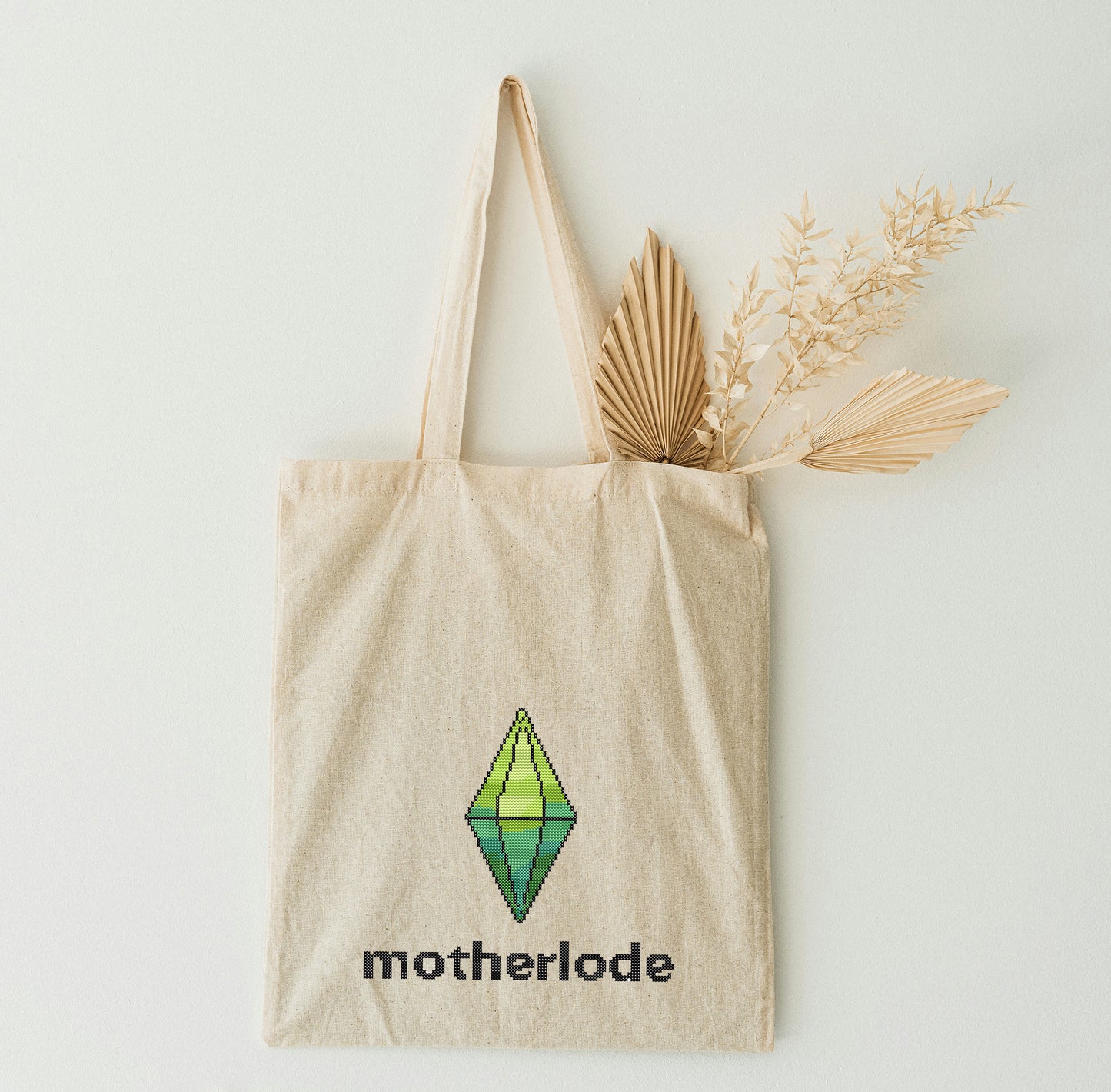 Beige tote bag with 'motherlode' and logo on the white wall