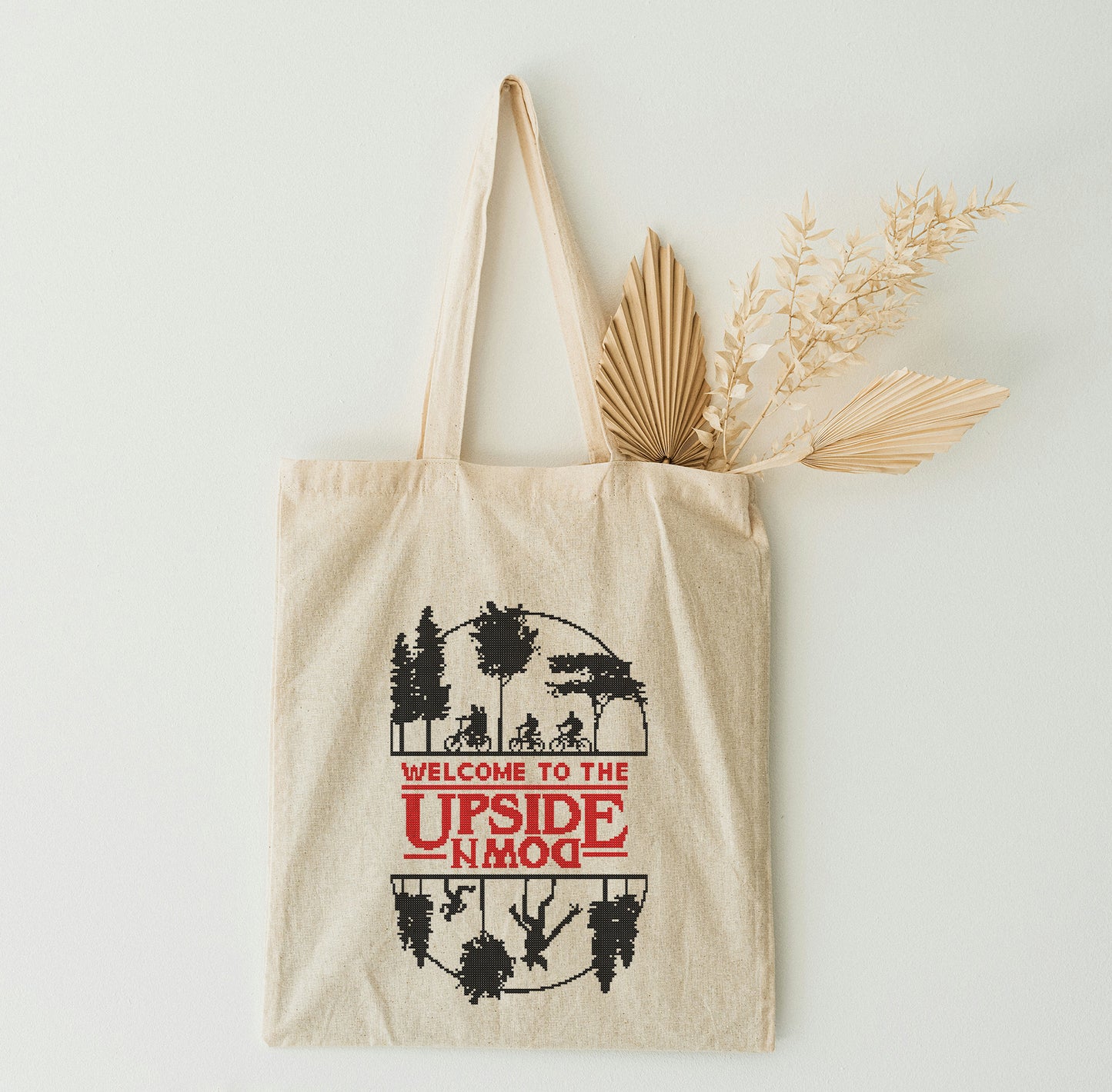 A beige tote bag with graphic design on a white wall