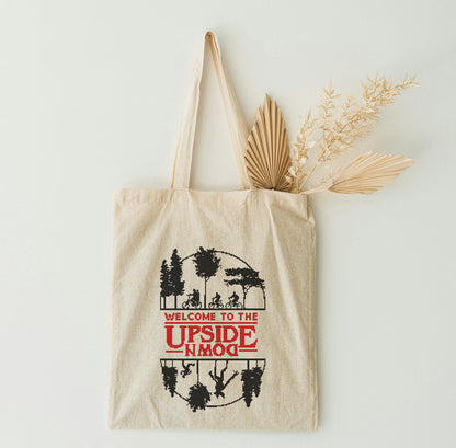 A beige tote bag with graphic design on a white wall