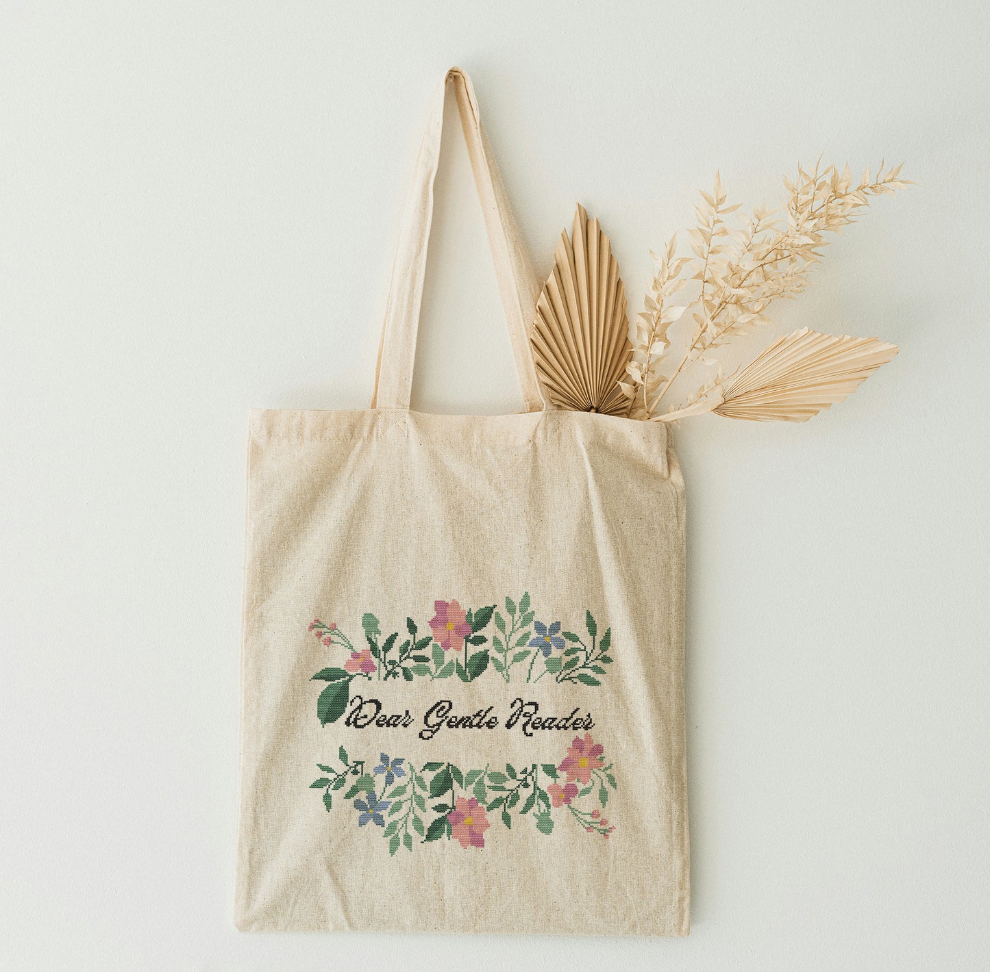 Beige tote bag with floral design and text on a light background