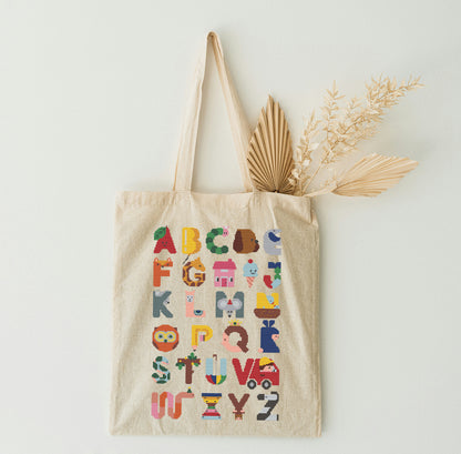 Beige tote bag with colorful alphabet design on a light background