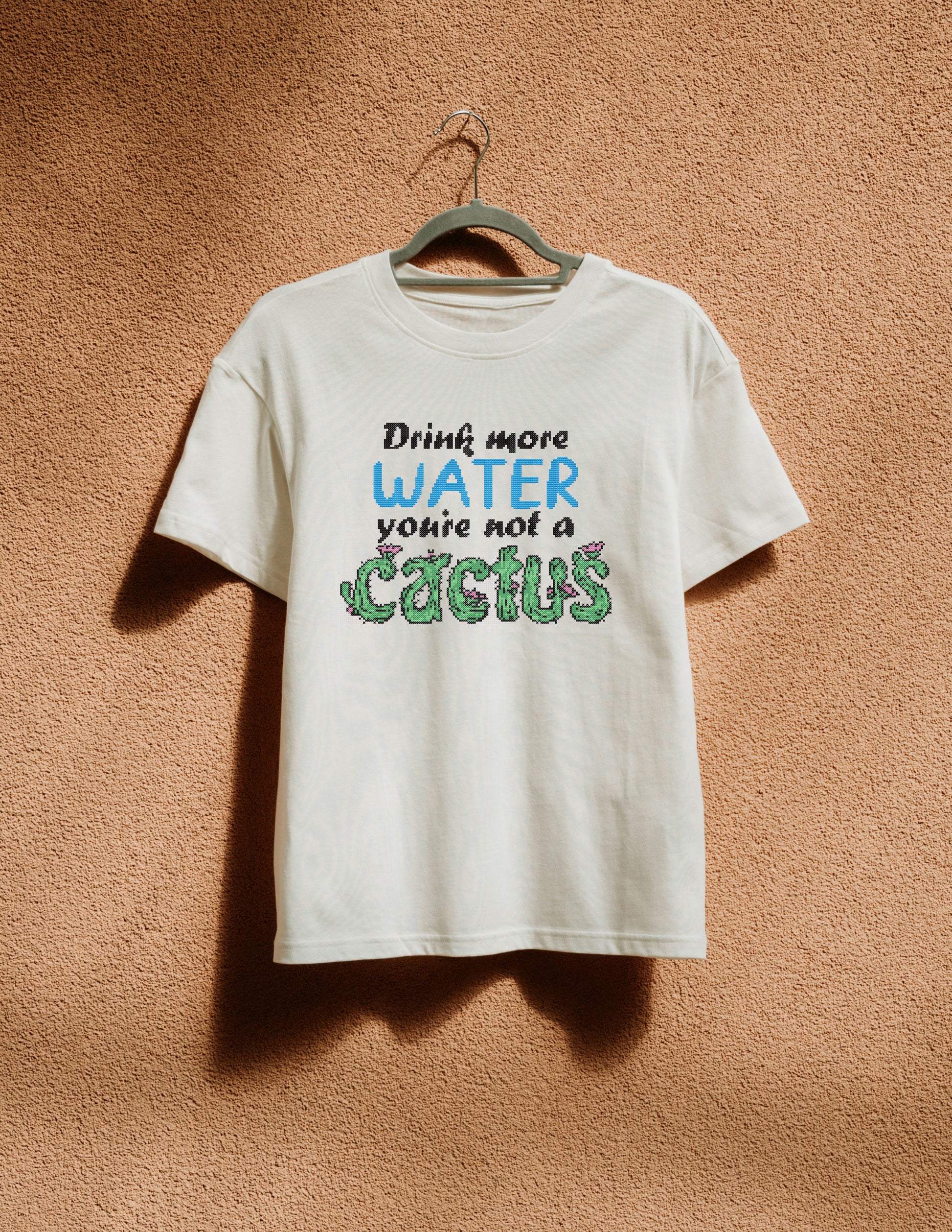 White t-shirt with humorous text on a hanger against a textured brown wall