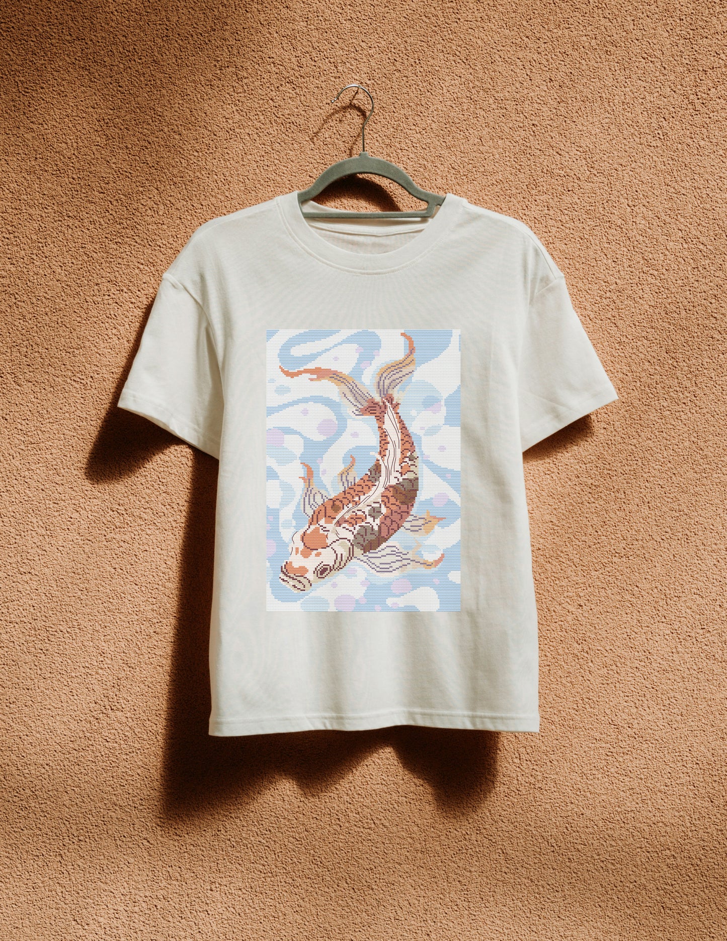 White t-shirt with a koi fish design on a beige background
