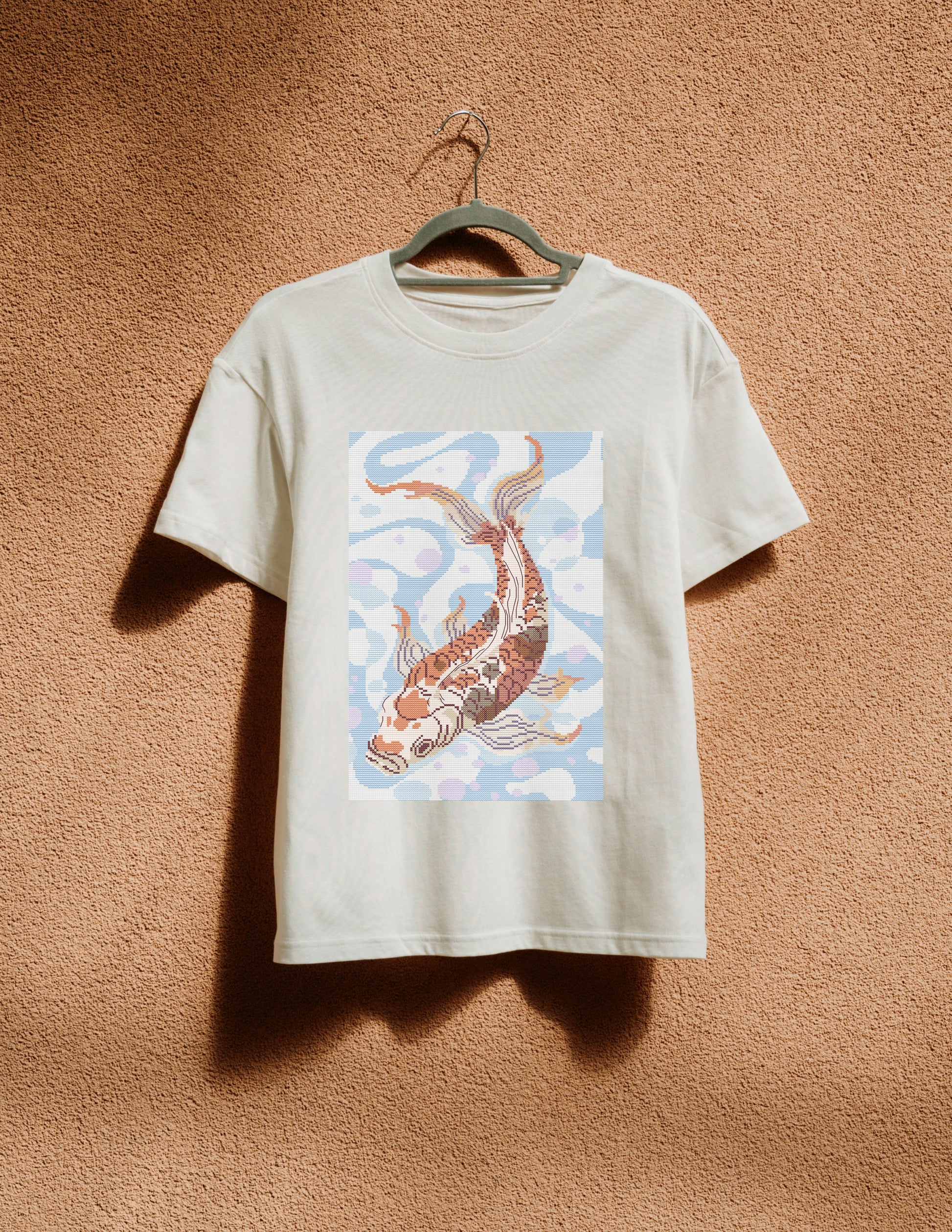 White t-shirt with a koi fish design on a beige background