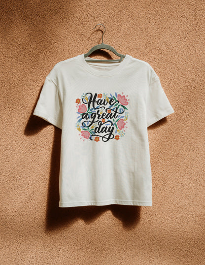 White t-shirt with colorful text and floral design on a hanger against a brown background