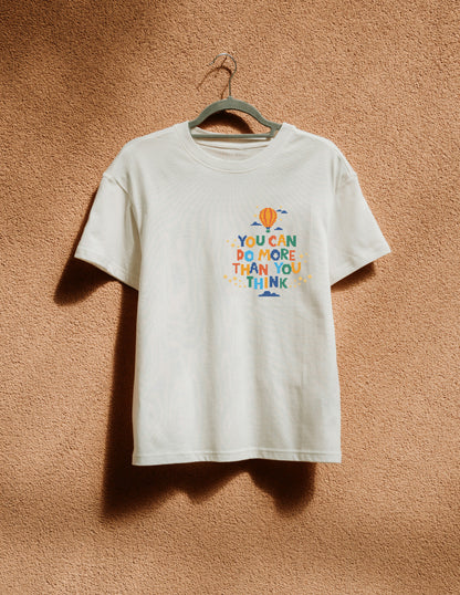 White t-shirt with colorful text and graphics on a beige wall