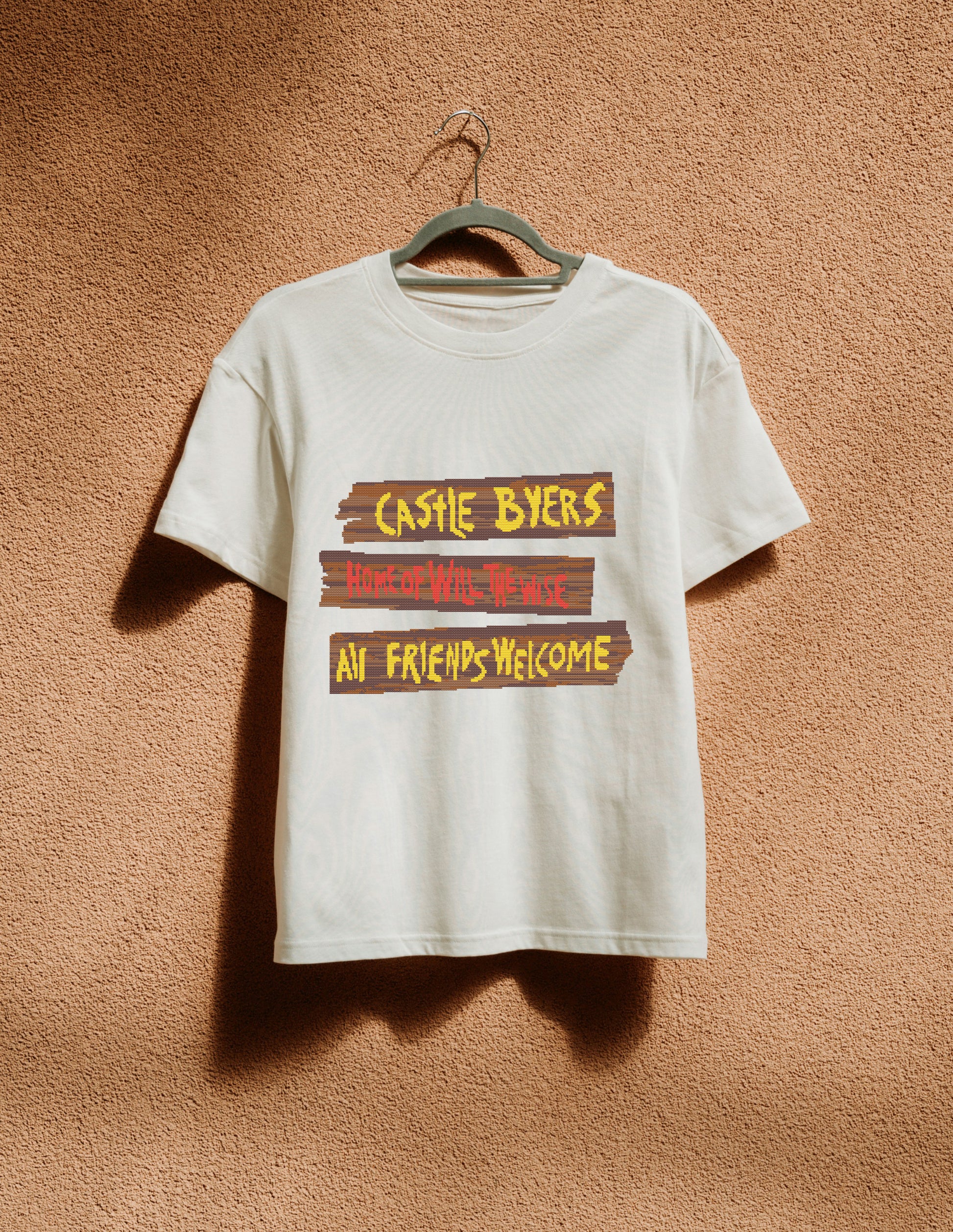 White t-shirt with text design on a hanger against a textured brown wall