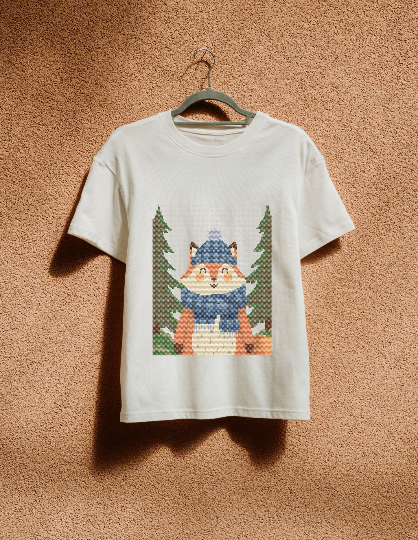 White t-shirt with a fox graphic hanging on a hanger against a brown textured wall.