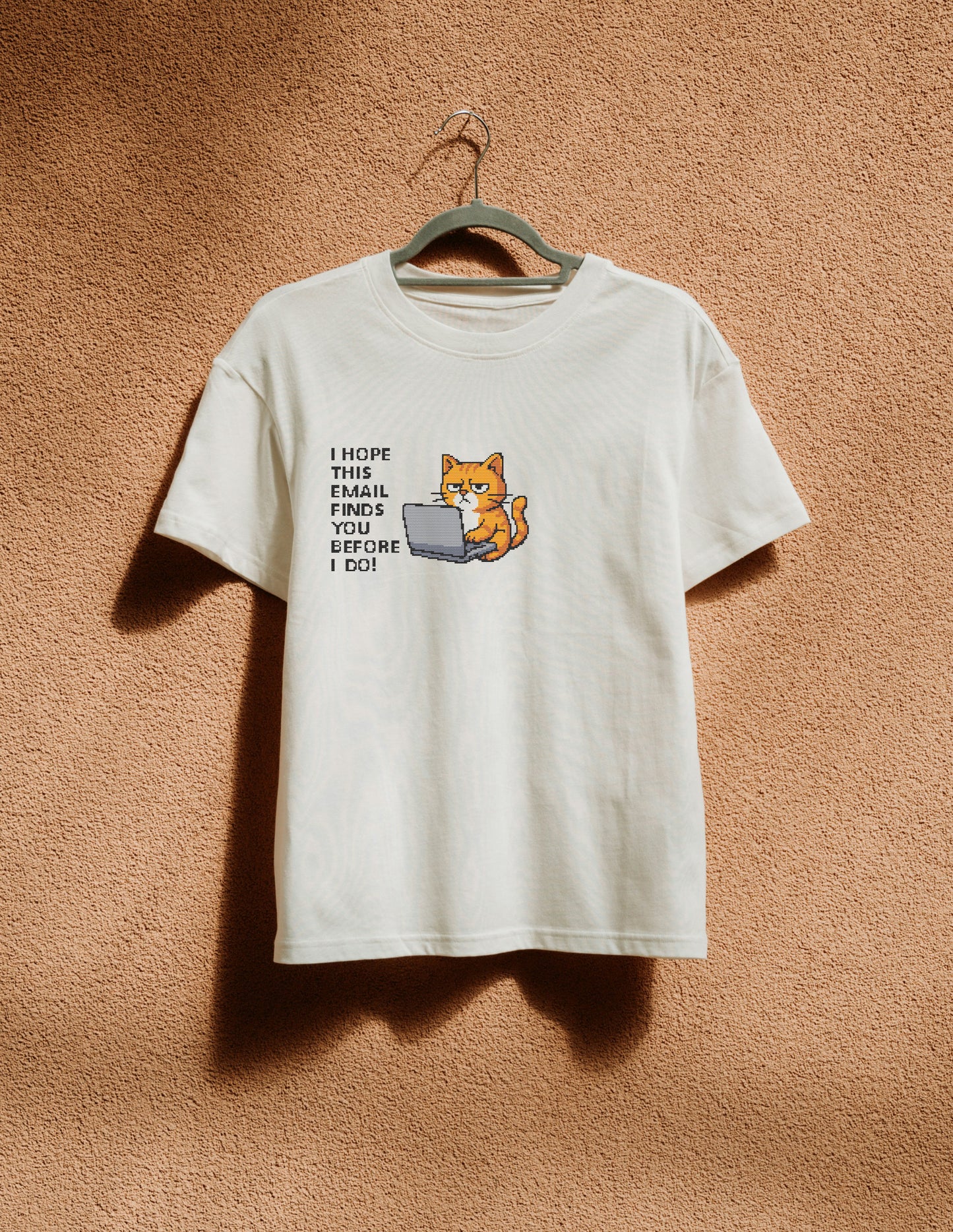 White t-shirt with a graphic of a cat using a laptop and text on a beige background