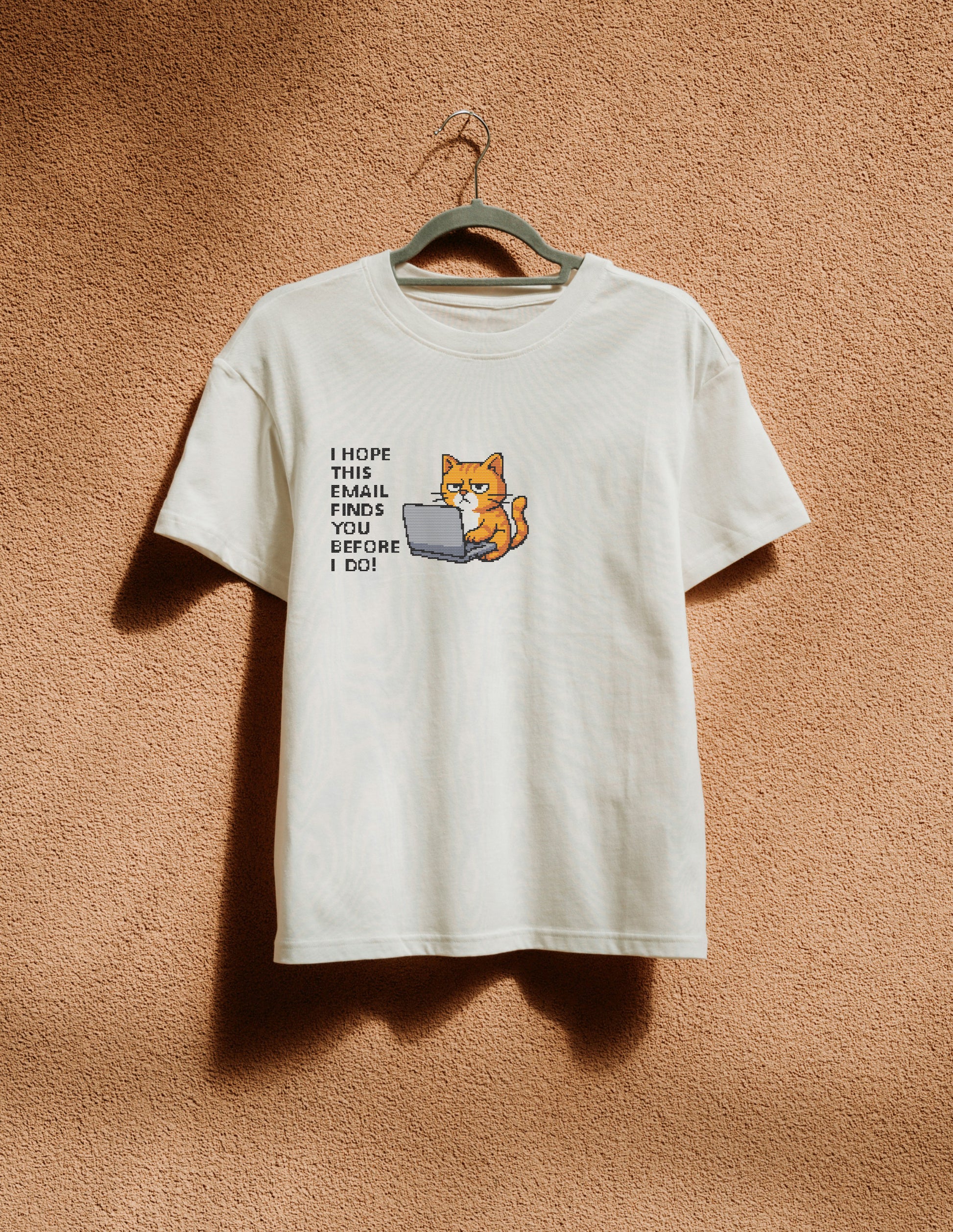 White t-shirt with a graphic of a cat using a laptop and text on a beige background