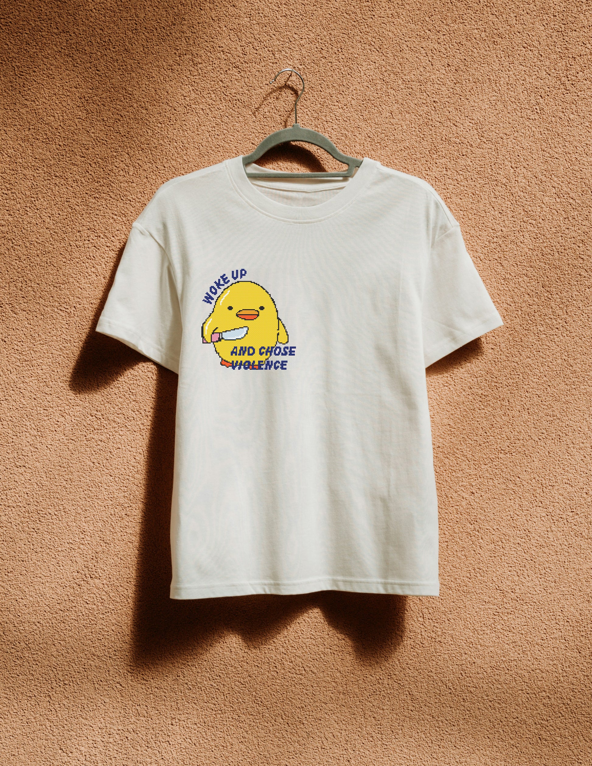 White t-shirt with a yellow character graphic and text on a brown textured background