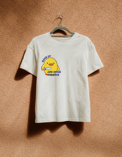 White t-shirt with a yellow character graphic and text on a brown textured background