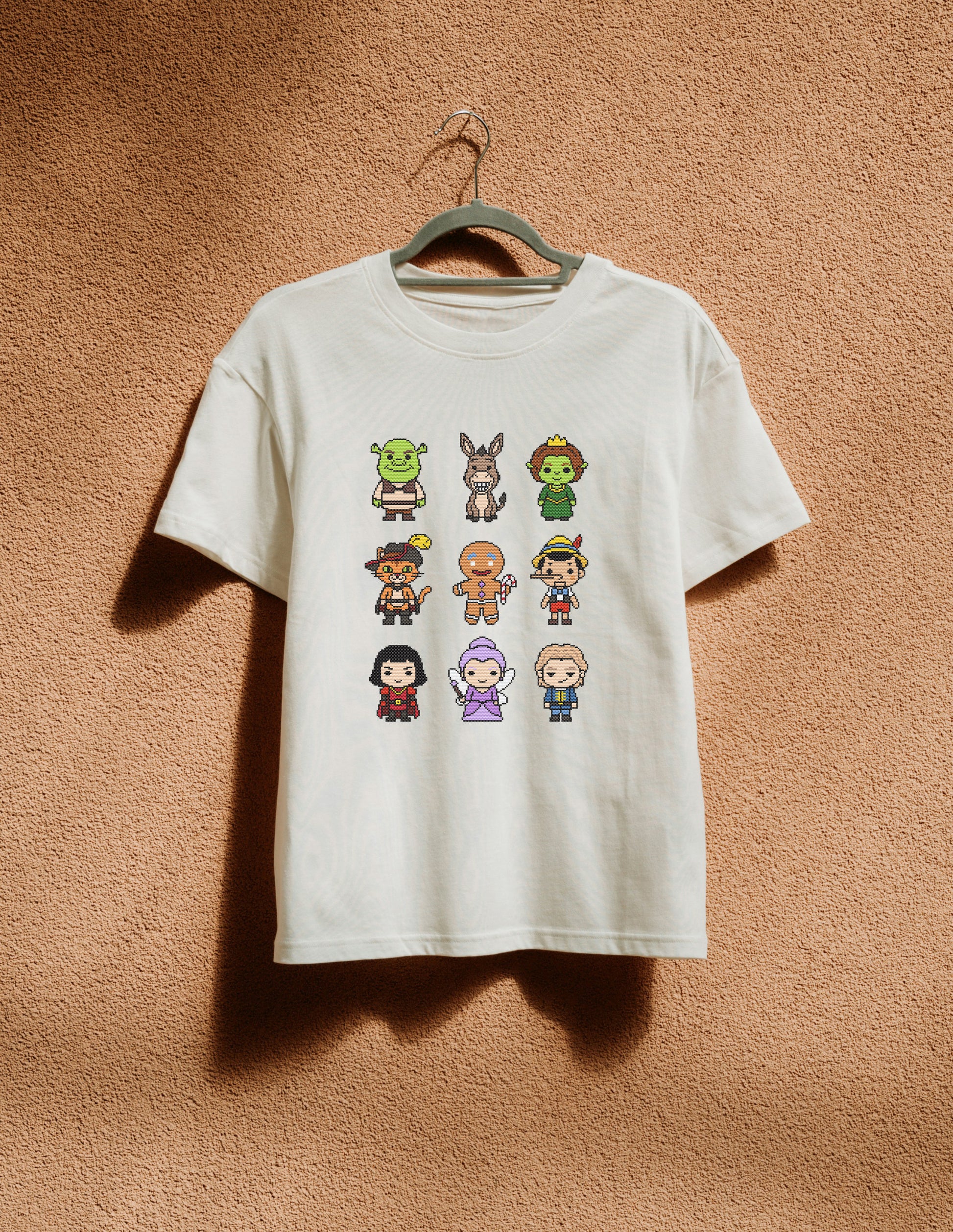 White t-shirt with pixel art character design on a beige background
