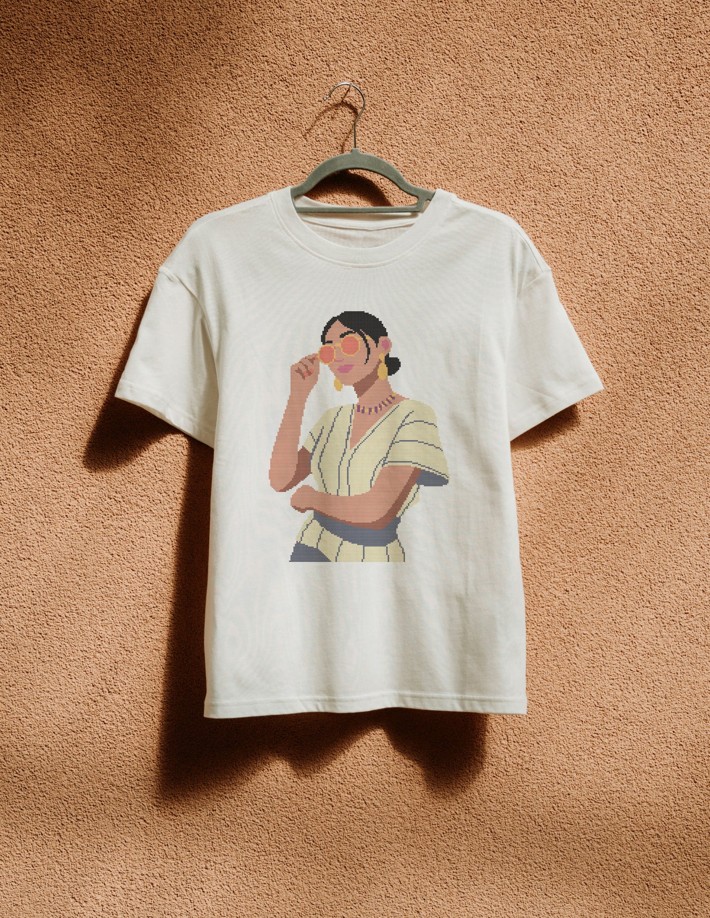 White t-shirt with a graphic of a woman on a beige wall