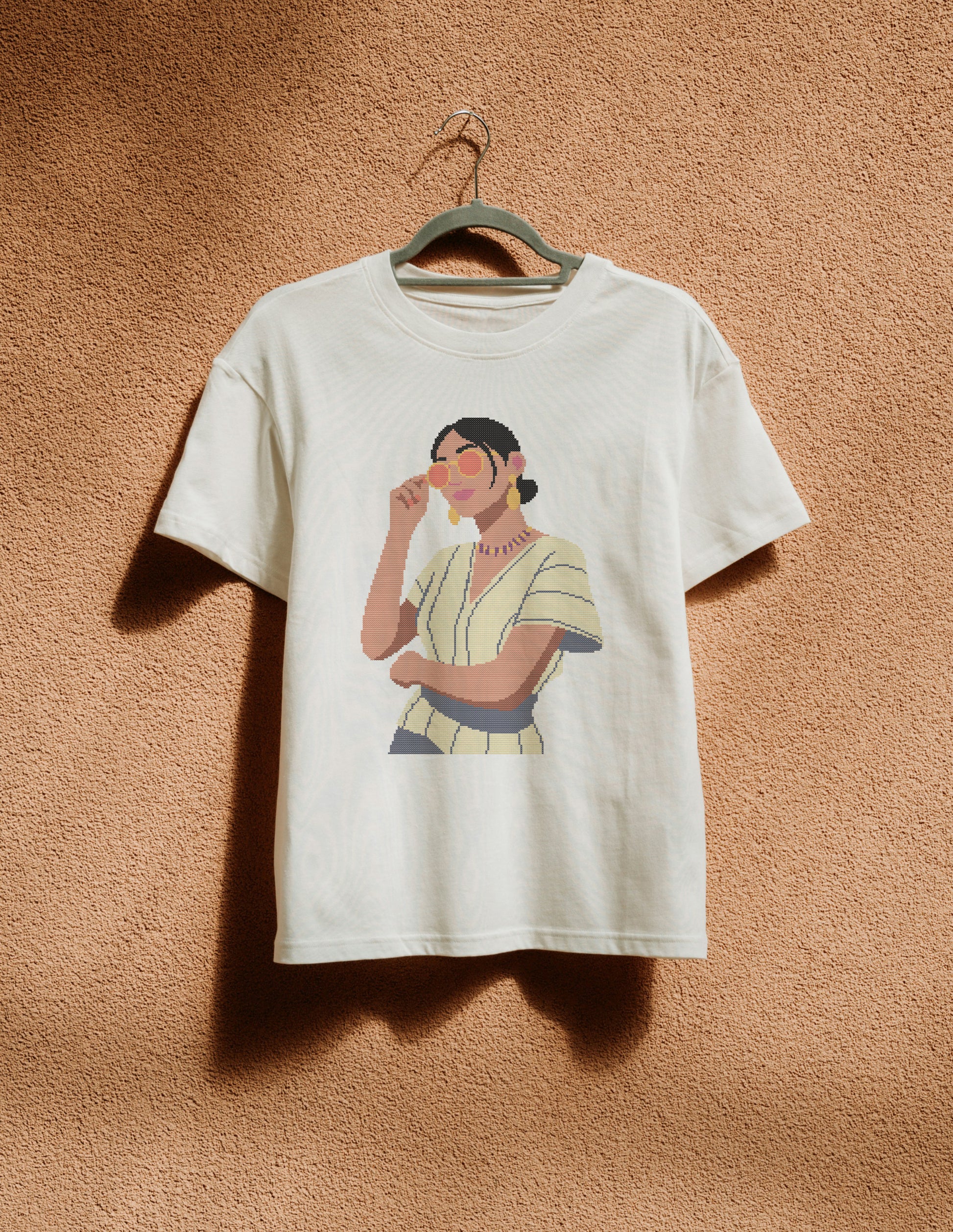 White t-shirt with a graphic of a woman on a beige wall