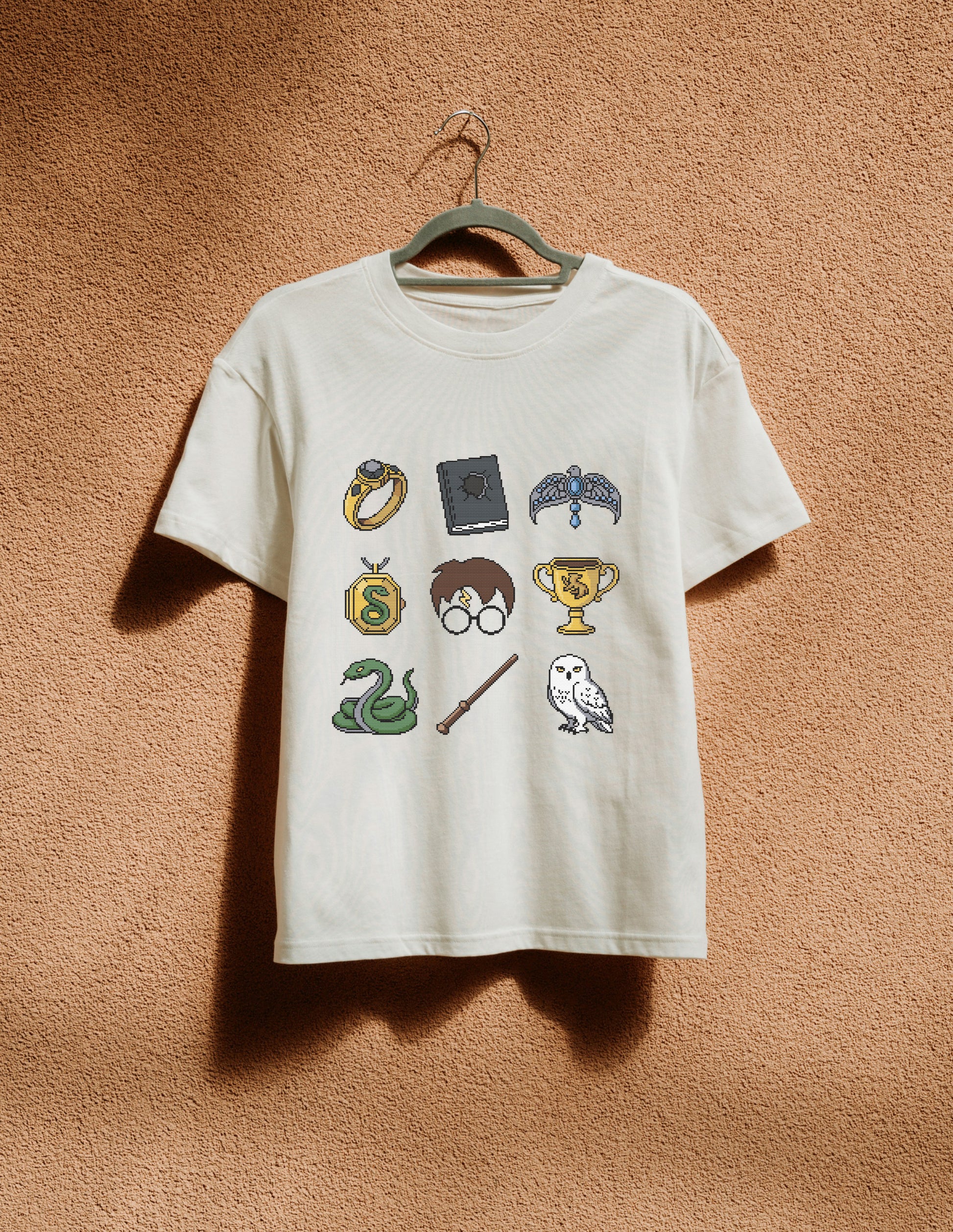 White t-shirt with Harry Potter-themed graphics on a beige wall