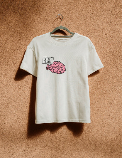 White t-shirt with a pink brain graphic and text on a beige wall