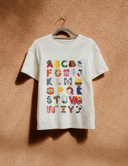 White t-shirt with colorful alphabet design on a hanger against a brown wall.